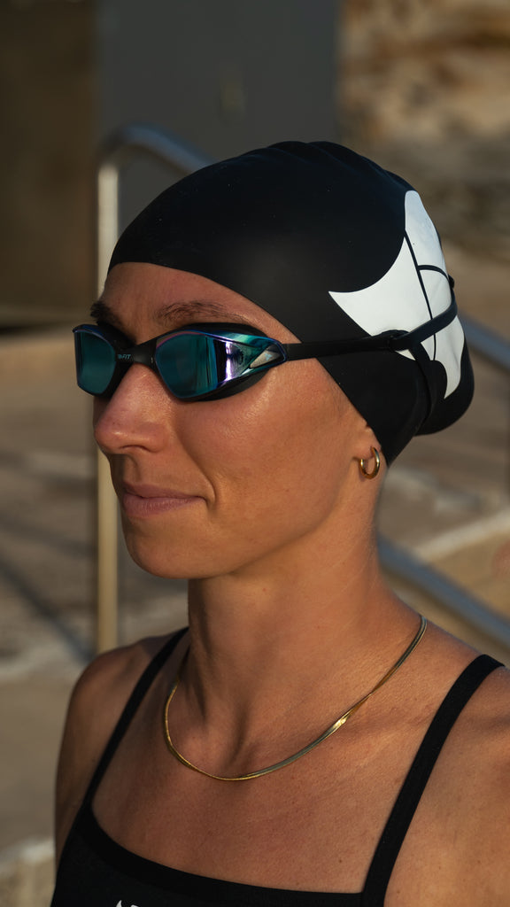 Women wearing TRI-FIT PROPEL Reversible Swimsuit with PROPEL Goggles and Swim Cap.